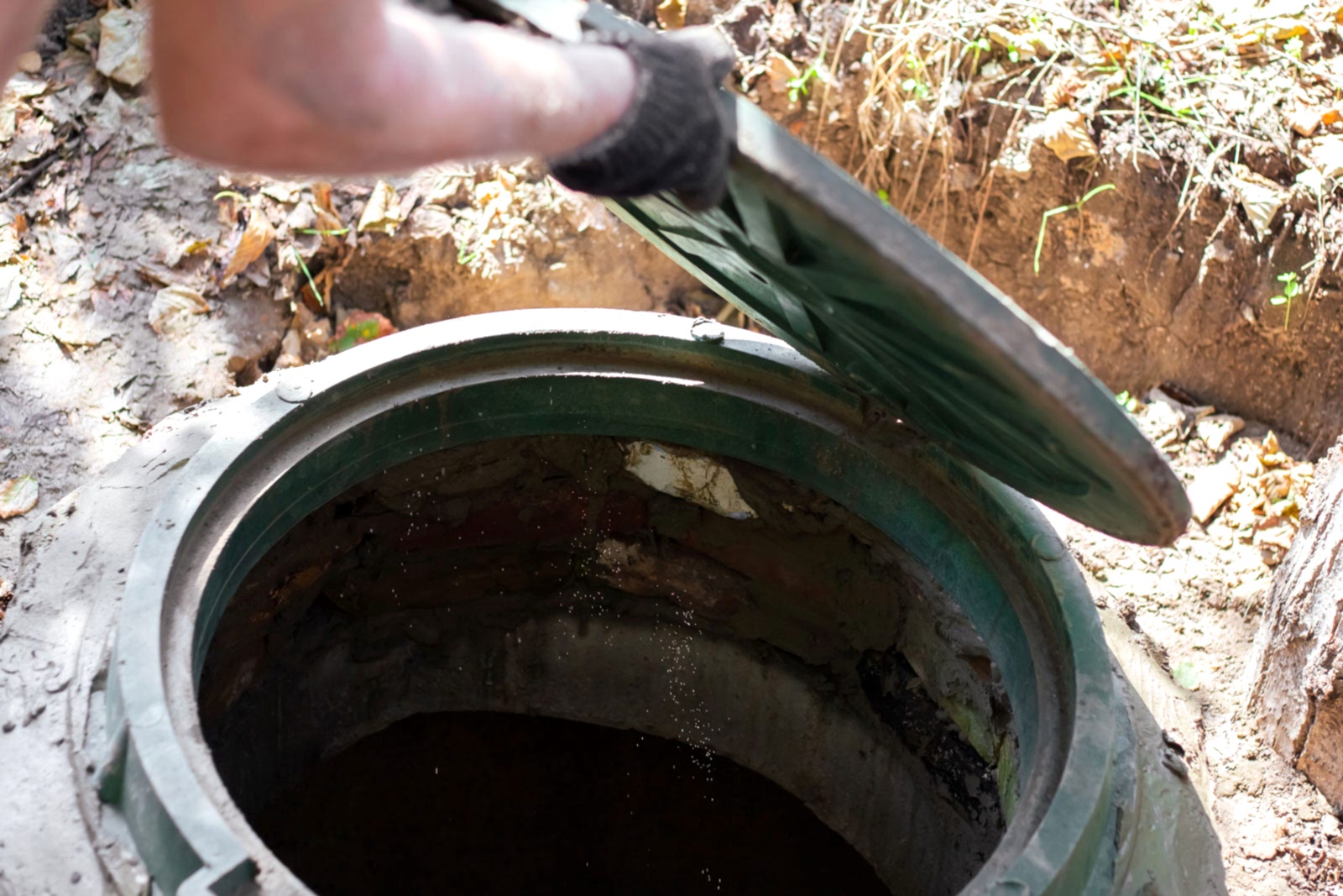 Skilled technician opening a sewer hatch for septic tank inspection and maintenance